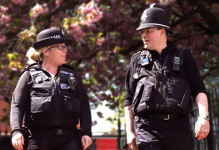 Two police officers in uniform walk outdoors